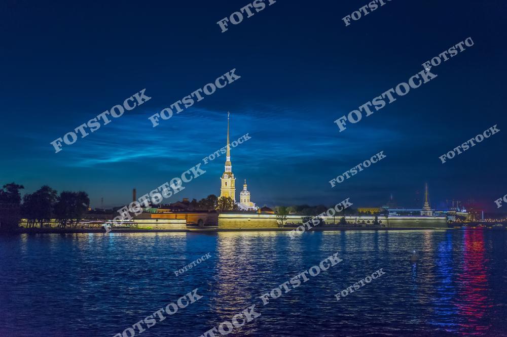 Живописный вид на Петропавловскую крепость в Санкт-Петербурге на фоне редких серебристых облаков — необычного атмосферного явления, наблюдаемого в северных широтах. Ночное небо с переливающимися облаками создаёт загадочную и романтичную атмосферу над северной столицей России. Историческая архитектура крепости и природное явление гармонично сочетаются, образуя уникальный городской пейзаж. Фотография идеально подходит для публикаций о природных феноменах, достопримечательностях Санкт-Петербурга, ночной фотографии, путешествиях по России и атмосферных городских видах.